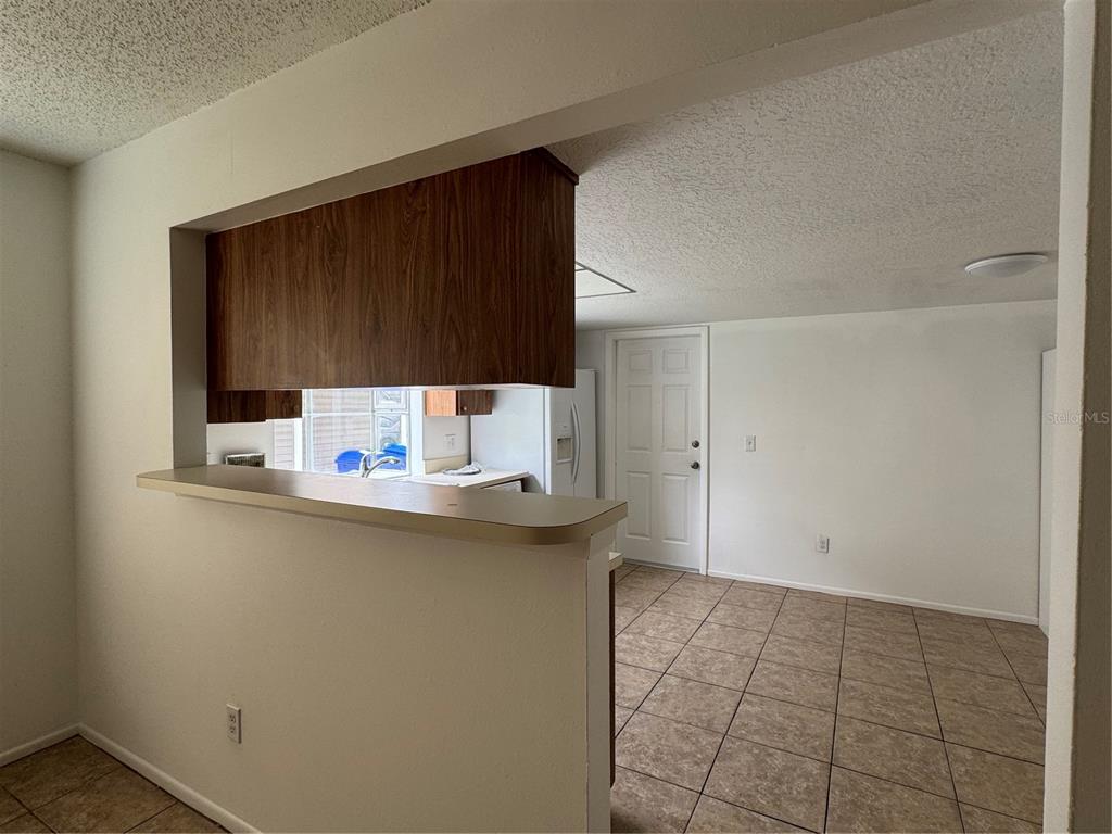 A view from a living area looking into a kitchen with a breakfast bar — 2352 PEBBLE BROOK ROAD, KISSIMMEE, FL