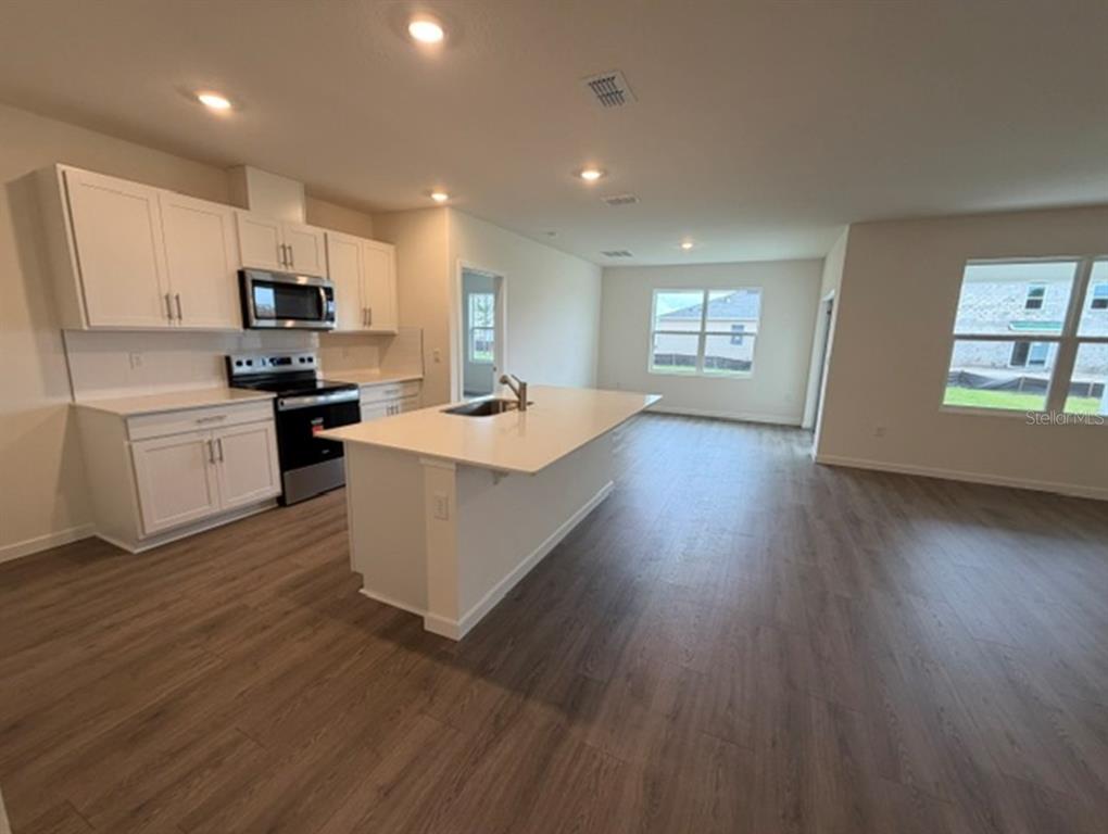 An empty room with light wood-look flooring, white walls, and a view of the entryway — 4922 MARSHELDER STREET, APOPKA, FL