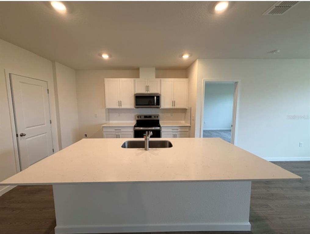 A kitchen island with a sink and dishwasher overlooks an open living area with water views — 4922 MARSHELDER STREET, APOPKA, FL