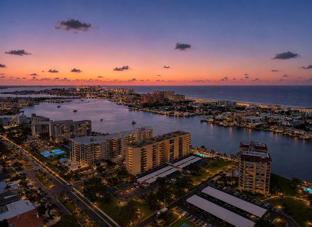 An aerial view of a coastal city at sunset with high-rise buildings and a waterway — 690 ISLAND WAY UNIT 501, CLEARWATER BEACH, FL