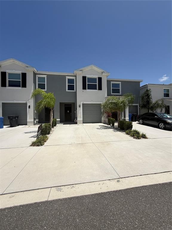 A row of two-story townhouses with gray and white exteriors, attached garages, and small palm trees — 191 MANGROVE SHADE CIRCLE, APOLLO BEACH, FL