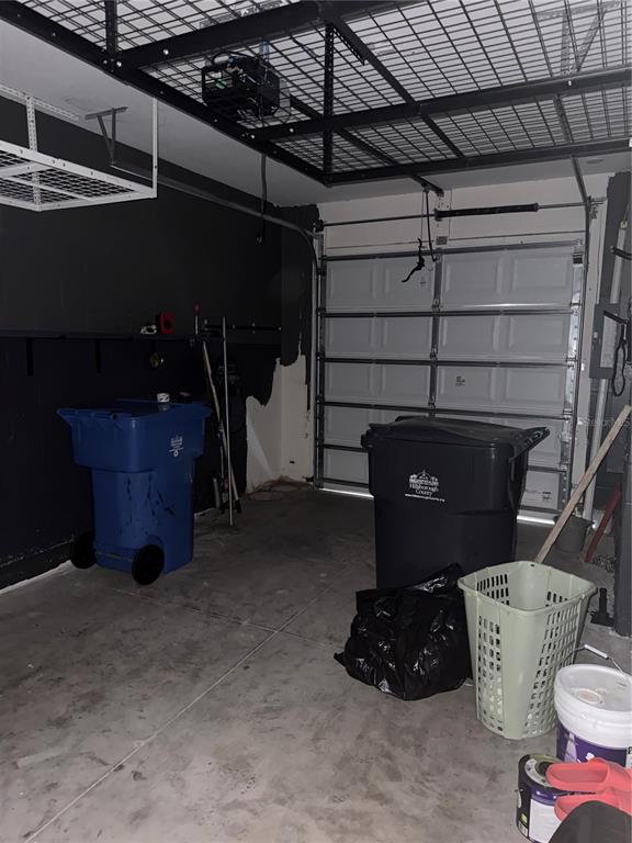 A garage with black walls, a ceiling storage rack, and two large trash bins — 191 MANGROVE SHADE CIRCLE, APOLLO BEACH, FL