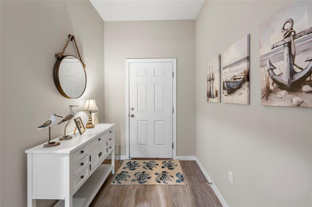 A coastal-themed entryway features a white console table, a round mirror, and nautical wall art — 12690 TANNENCREST DRIVE, RIVERVIEW, FL