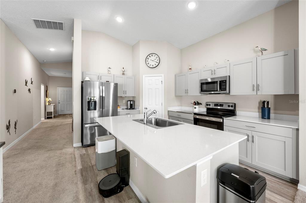 A modern kitchen features light gray cabinetry, white countertops, a central island, and stainless steel appliances — 12690 TANNENCREST DRIVE, RIVERVIEW, FL