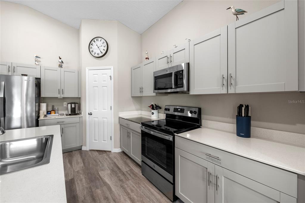 A kitchen features gray cabinets, stainless steel appliances, white countertops, and wood-look flooring — 12690 TANNENCREST DRIVE, RIVERVIEW, FL