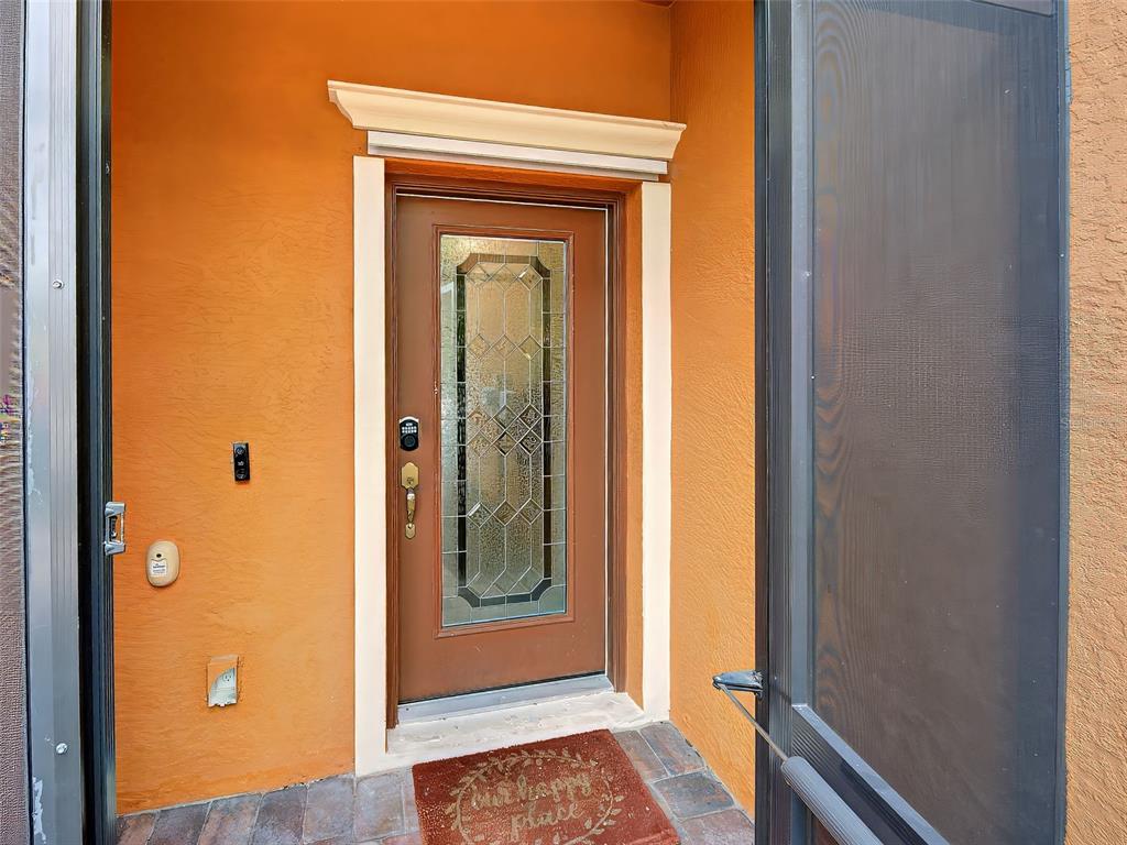 A brown front door with a decorative glass insert is set in an orange wall — 20217 LAGENTE CIRCLE, VENICE, FL