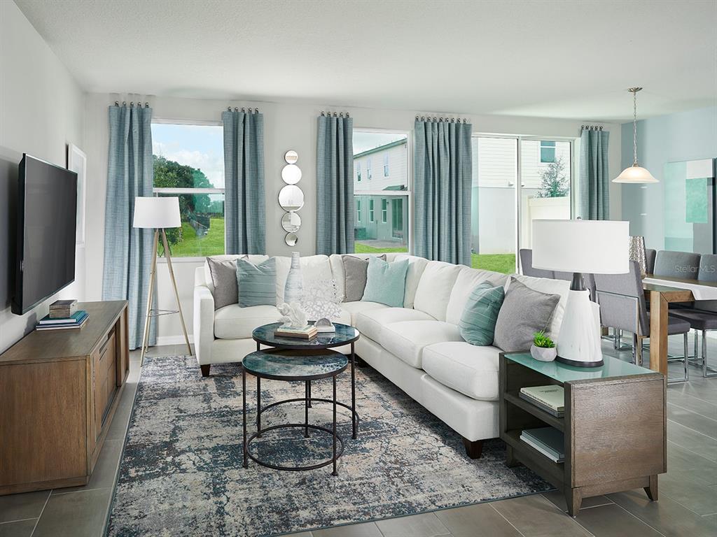 A living room features a white sectional sofa, blue curtains, and a patterned area rug — 4561 RANGELAND WAY, ST CLOUD, FL