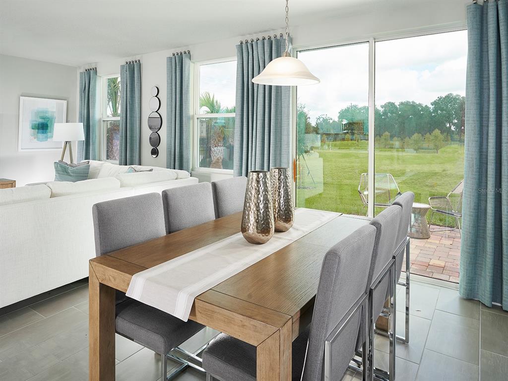 A dining room with a wooden table and gray chairs overlooks a patio and yard — 4561 RANGELAND WAY, ST CLOUD, FL