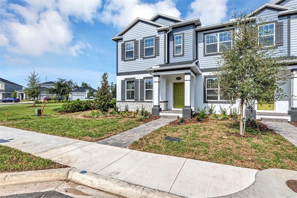 A two-story townhouse with gray siding, stone accents, and a green front door — 518 LADY PALM STREET, APOPKA, FL