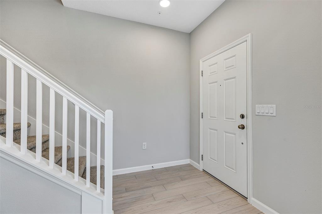 An entryway features light wood-look tile flooring, a carpeted staircase with white railings, and a door — 518 LADY PALM STREET, APOPKA, FL
