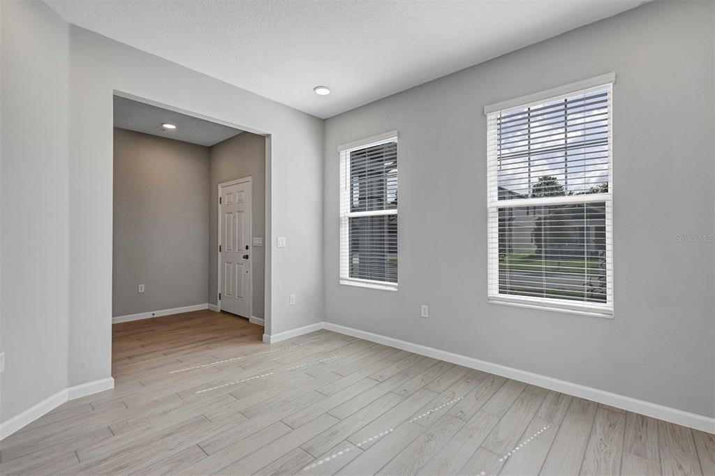 An empty room with light wood-look tile flooring, gray walls, and two windows with blinds — 518 LADY PALM STREET, APOPKA, FL