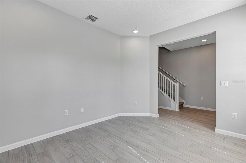 An empty room with light gray walls, wood-look flooring, and an opening to a staircase — 518 LADY PALM STREET, APOPKA, FL
