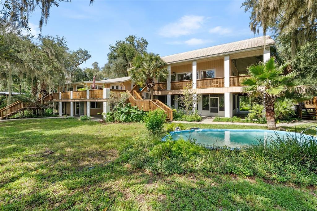 A two-story house with a large wooden deck, a pool, and surrounding trees — 2033 SE HIGHWAY 317, OLD TOWN, FL