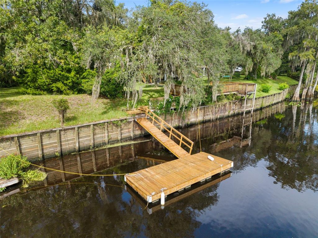 An aerial view of a wooden dock extending from a bulkhead into a dark river — 2033 SE HIGHWAY 317, OLD TOWN, FL
