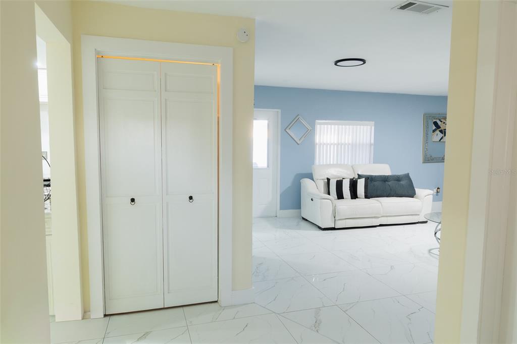 A white closet door stands in a hallway leading to a living room with tile floors — 4710 SHALE PLACE, TAMPA, FL