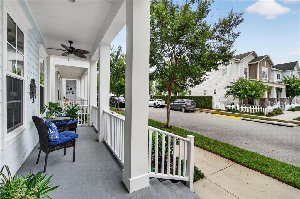 A covered front porch with seating overlooks a suburban street with houses and parked cars — 1356 CAP ROCK DRIVE, CELEBRATION, FL