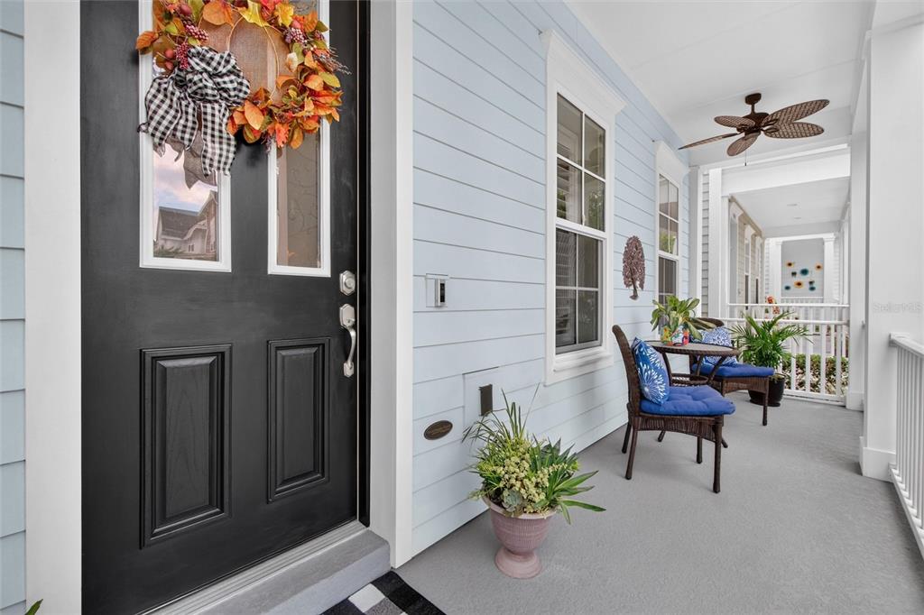 A light blue porch features a black front door, wicker seating, and a ceiling fan — 1356 CAP ROCK DRIVE, CELEBRATION, FL