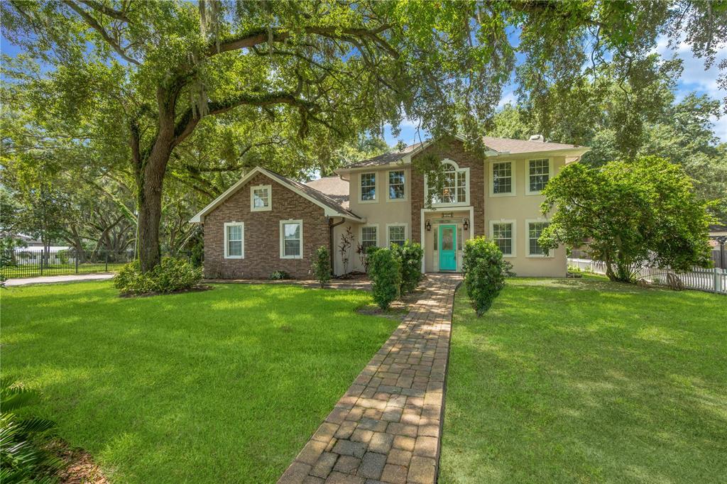 A two-story house with a brick and stucco exterior, a turquoise front door, and trees — 1507 W WINDHORST ROAD, BRANDON, FL