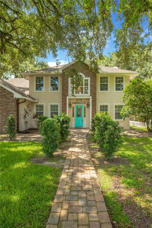 A two-story house with a brick facade, a teal front door, and a stone walkway — 1507 W WINDHORST ROAD, BRANDON, FL