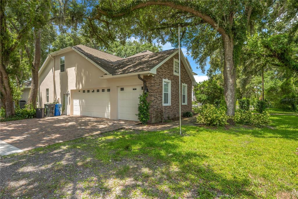 A side view of a house with a brick exterior, a garage, and a driveway — 1507 W WINDHORST ROAD, BRANDON, FL