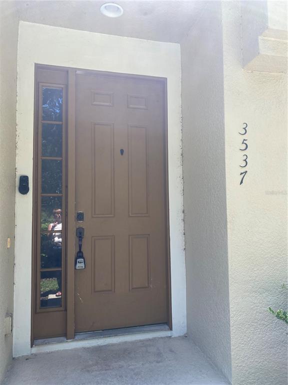 A brown front door with a side window and a lockbox sits under a recessed light — 3537 CLAY BRICK ROAD UNIT 3537, HARMONY, FL