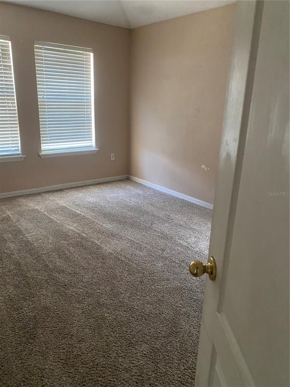 An empty bedroom features beige walls, carpeted flooring, and two windows with white blinds — 3537 CLAY BRICK ROAD UNIT 3537, HARMONY, FL
