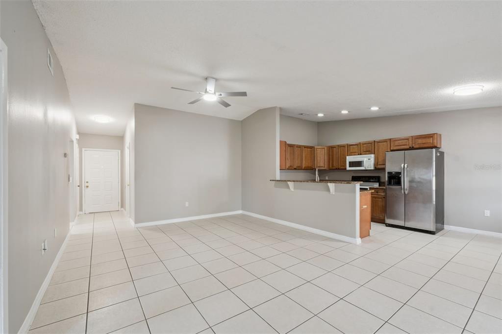An empty room with light-colored tile flooring, a ceiling fan, and a sliding glass door — 3122 LORRY LANE, ORLANDO, FL