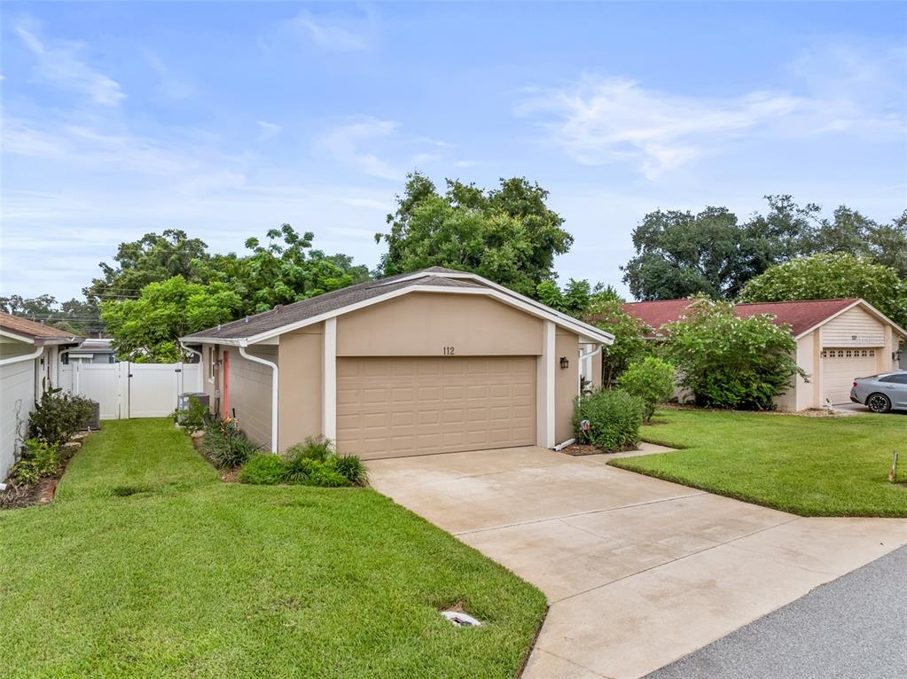 A tan single-story house with a two-car garage and a concrete driveway — 112 MAYFAIR CT UNIT 112, SANFORD, FL