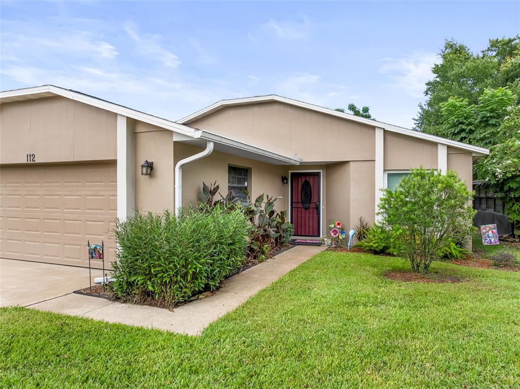 A single-story house with a tan exterior, a two-car garage, and a front walkway — 112 MAYFAIR CT UNIT 112, SANFORD, FL