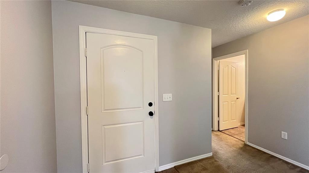 A white interior door with black hardware sits next to a doorway leading to another room — 13609 LARANJA STREET, CLERMONT, FL