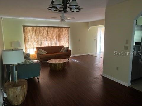 A living room features dark wood flooring, a sofa, a coffee table, and a ceiling fan — 7506 SPINNAKER BOULEVARD, ENGLEWOOD, FL