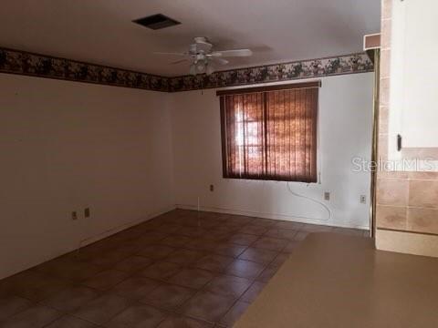An empty room with tile flooring, a ceiling fan, and a window with brown blinds — 7506 SPINNAKER BOULEVARD, ENGLEWOOD, FL