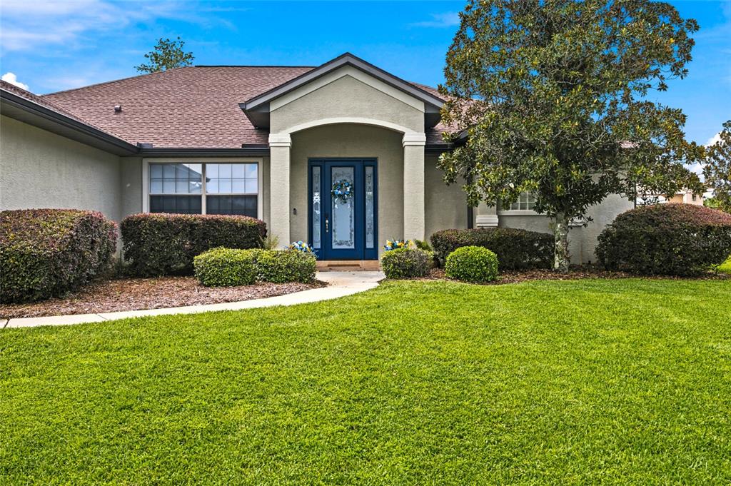 A single-story house with a blue front door, a covered entryway, and a manicured lawn — 9640 SE 61 TERRACE, BELLEVIEW, FL