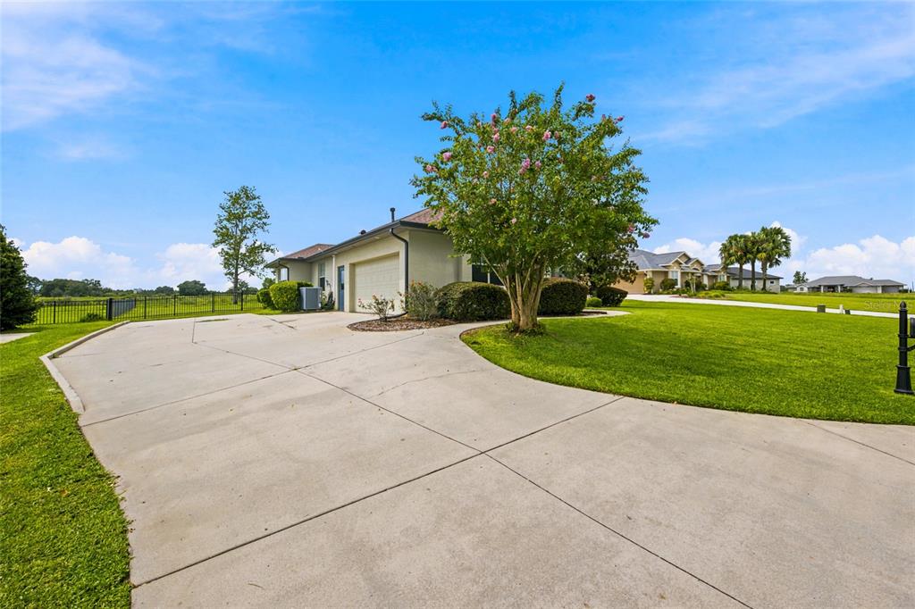 A concrete driveway leads to the side-entry garage of a house with a large lawn — 9640 SE 61 TERRACE, BELLEVIEW, FL