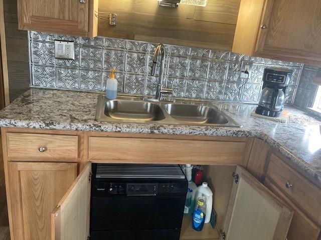 A kitchen sink area features oak cabinets, granite countertops, and a metallic patterned backsplash — 800 32ND AVENUE S UNIT 227, ST PETERSBURG, FL