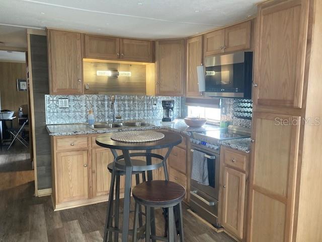 A kitchen features oak cabinets, a tiled backsplash, a small dining table, and stainless appliances — 800 32ND AVENUE S UNIT 227, ST PETERSBURG, FL
