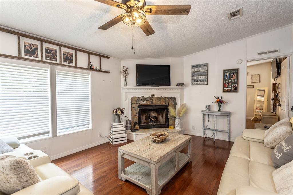 A living room features a stone fireplace, a wooden coffee table, and a ceiling fan — 1013 FOREST PARK STREET, BUNNELL, FL