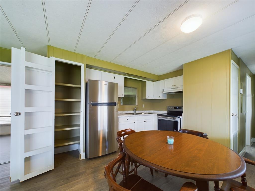 A kitchen with olive walls, white cabinets, stainless steel appliances, and a wooden dining table — 3502 DELAWARE AVENUE, SEBRING, FL