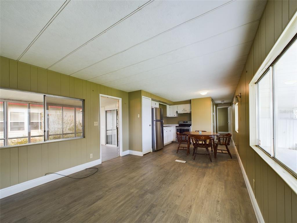 An open-concept kitchen and dining area with wood-look flooring and olive green paneled walls — 3502 DELAWARE AVENUE, SEBRING, FL
