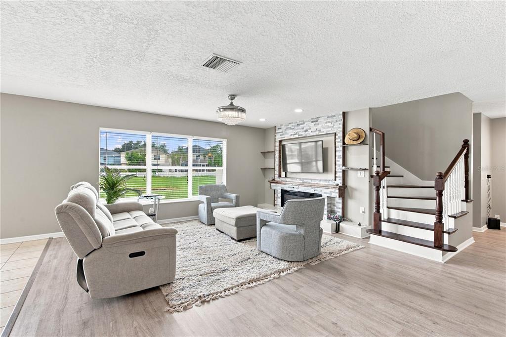 A living room features a stone fireplace, a staircase, and a large window with blinds — 10922 SUBTLE TRAIL DRIVE, RIVERVIEW, FL