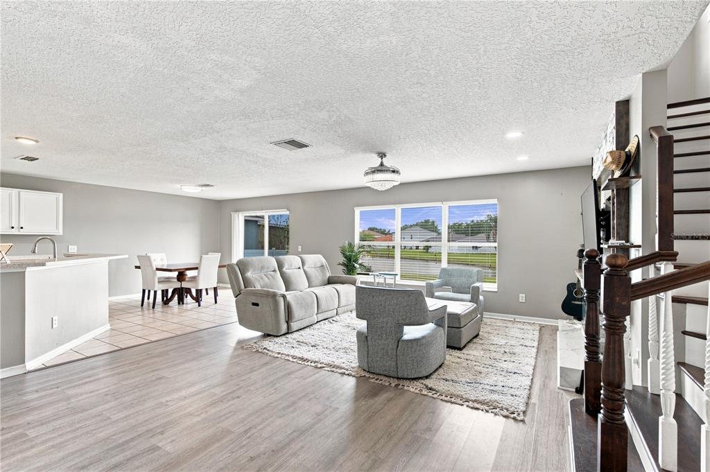 An open-concept living and dining area features light gray walls, wood-look flooring, and large windows — 10922 SUBTLE TRAIL DRIVE, RIVERVIEW, FL