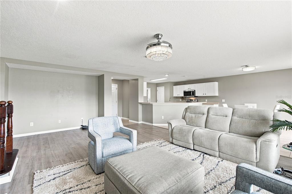 A living room with light gray walls, wood-look flooring, a sectional sofa, and a ceiling fan — 10922 SUBTLE TRAIL DRIVE, RIVERVIEW, FL