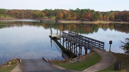 A wooden pier extends into a calm lake with a boat ramp in the foreground — 297 W WHITMARSH COURT, CITRUS SPRINGS, FL