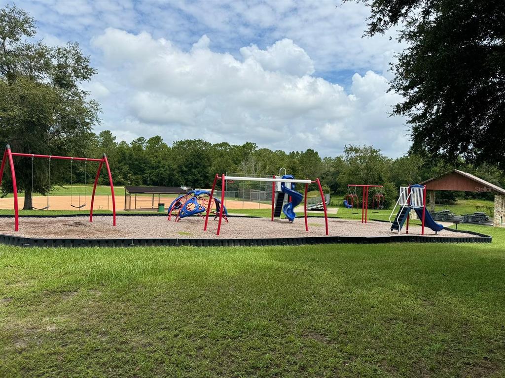 A playground with swings, a climbing structure, and slides sits on a wood-chipped surface — 297 W WHITMARSH COURT, CITRUS SPRINGS, FL
