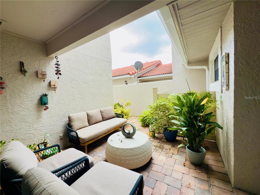 A covered outdoor patio features a sofa, two chairs, a round table, and potted plants — 8113 BREEZE COVE LANE, ORLANDO, FL