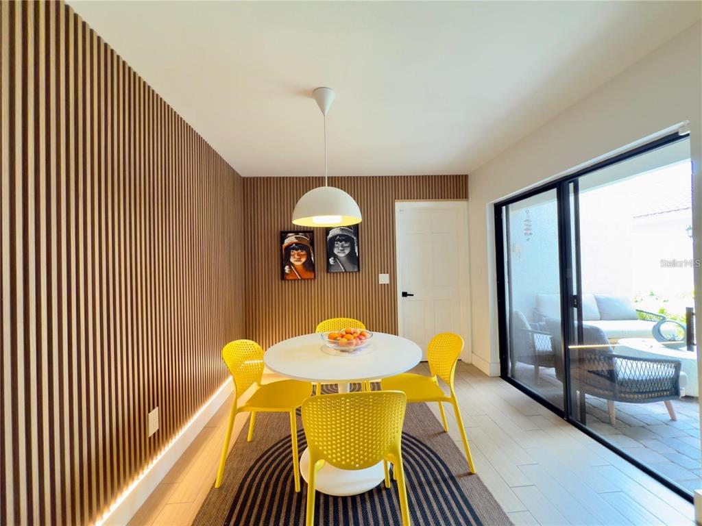 A dining room features a white round table, yellow chairs, and wood-slat accent walls — 8113 BREEZE COVE LANE, ORLANDO, FL