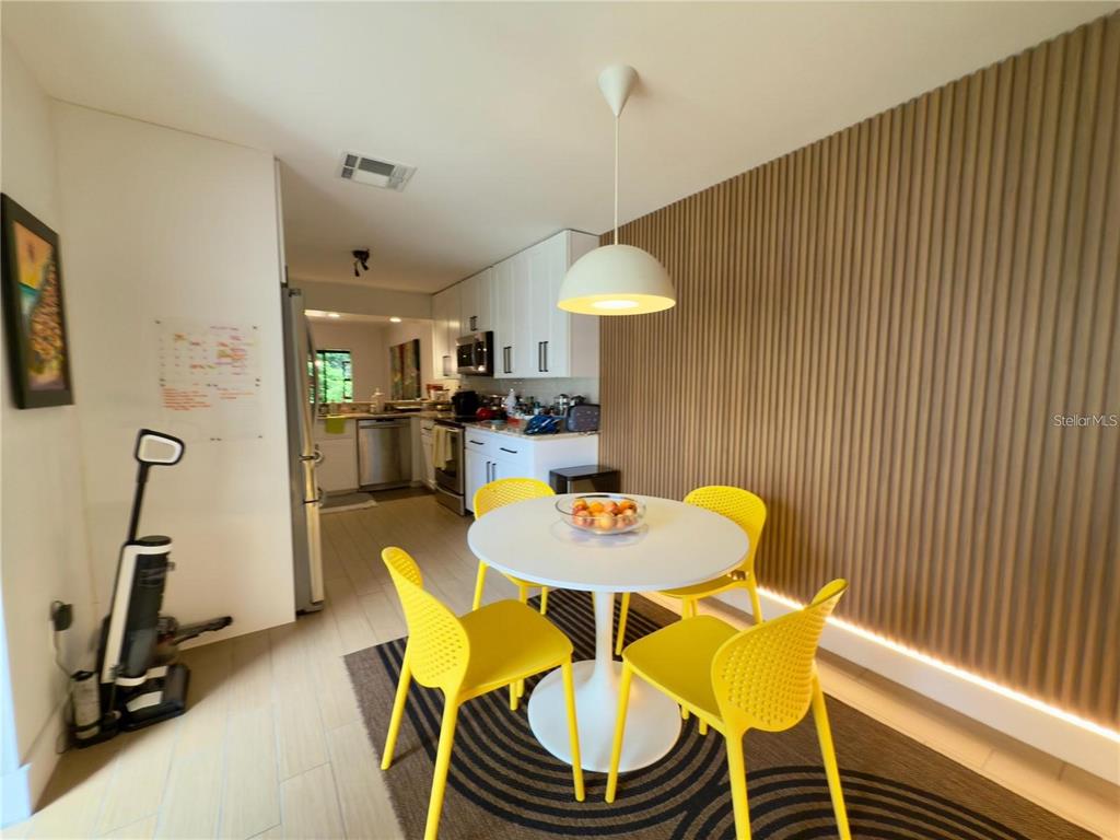 A dining area with a round white table, yellow chairs, and a slatted wood wall — 8113 BREEZE COVE LANE, ORLANDO, FL