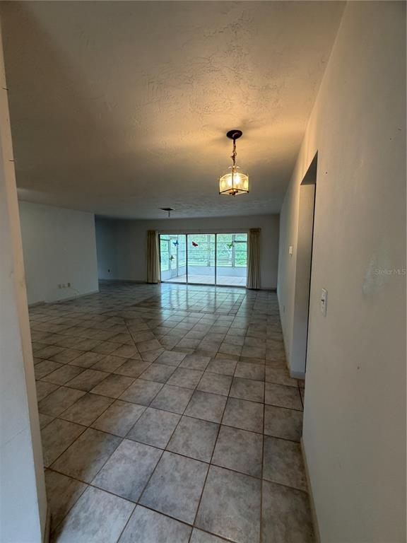 An open-concept living area features light-colored tile flooring and a sliding glass door to a lanai — 29768 67TH STREET N, CLEARWATER, FL
