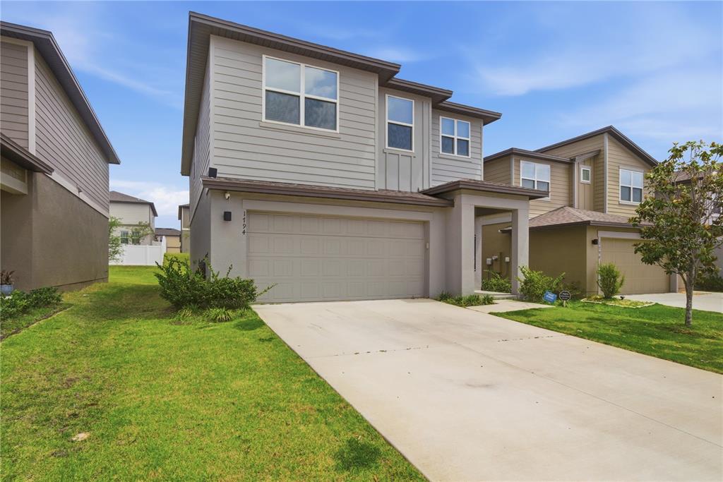 A two-story gray house with a two-car garage and a front yard — 1794 SUNDANCE CHASE ROAD, MINNEOLA, FL