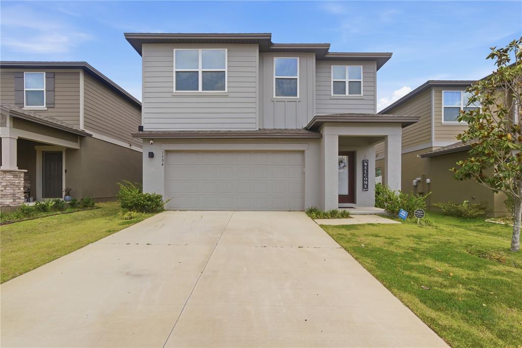 A two-story suburban house with gray siding, a two-car garage, and a concrete driveway — 1794 SUNDANCE CHASE ROAD, MINNEOLA, FL
